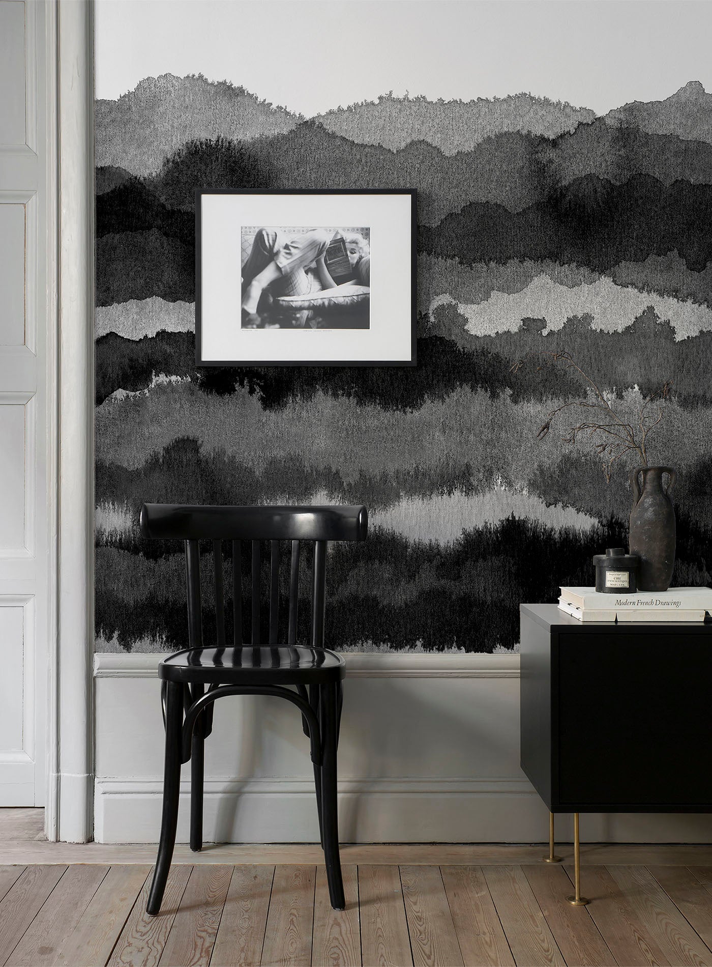 Midnatt wall mural by Sandberg in black and grey watercolour hills, behind a black bentwood chair and dark sideboard