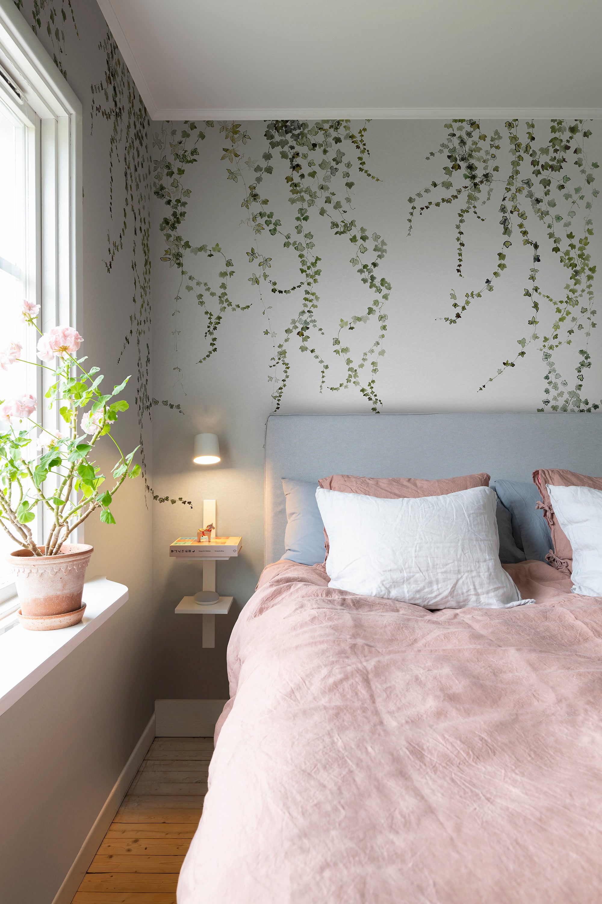 Aralia wall mural by Sandberg in green, cascading ivy on grey behind a bed with blush linen bedding