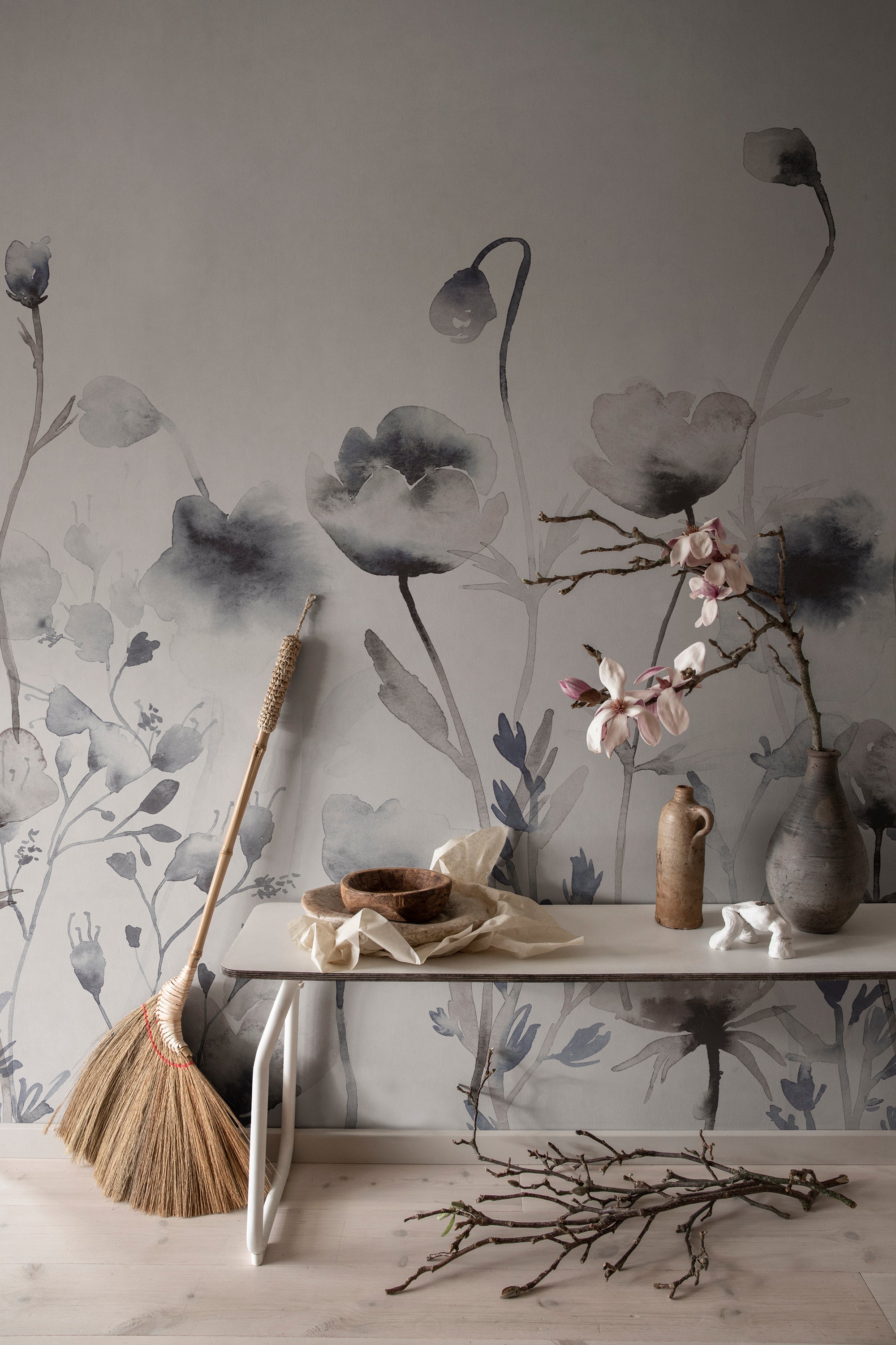 Morängen Floral wall mural by Sandberg in grey-blue behind a console table with magnolia branches and rustic pottery