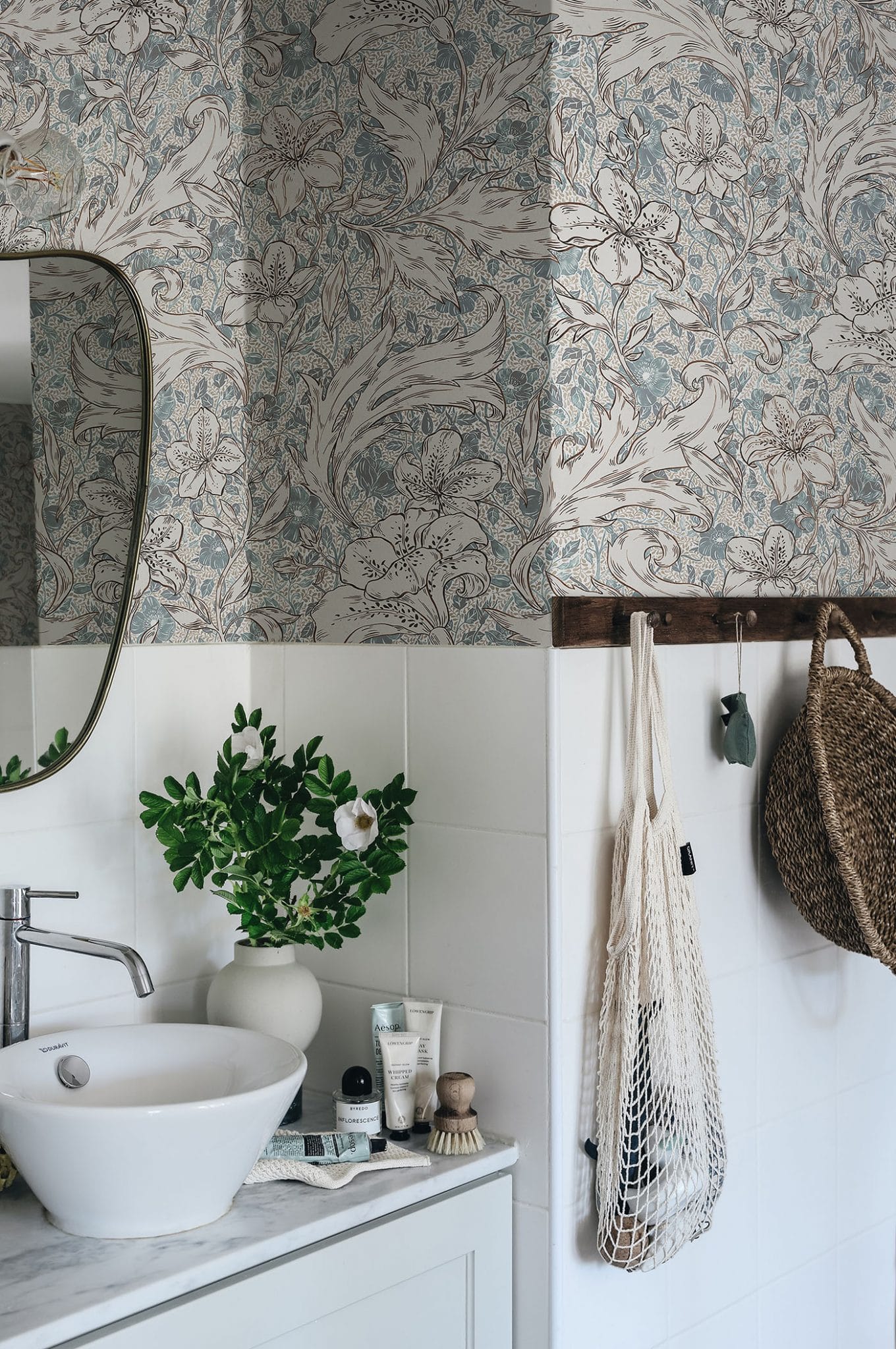 Mattias wallpaper by Sandberg in blue-grey floral design above white tiles in a bathroom with basin and mirror