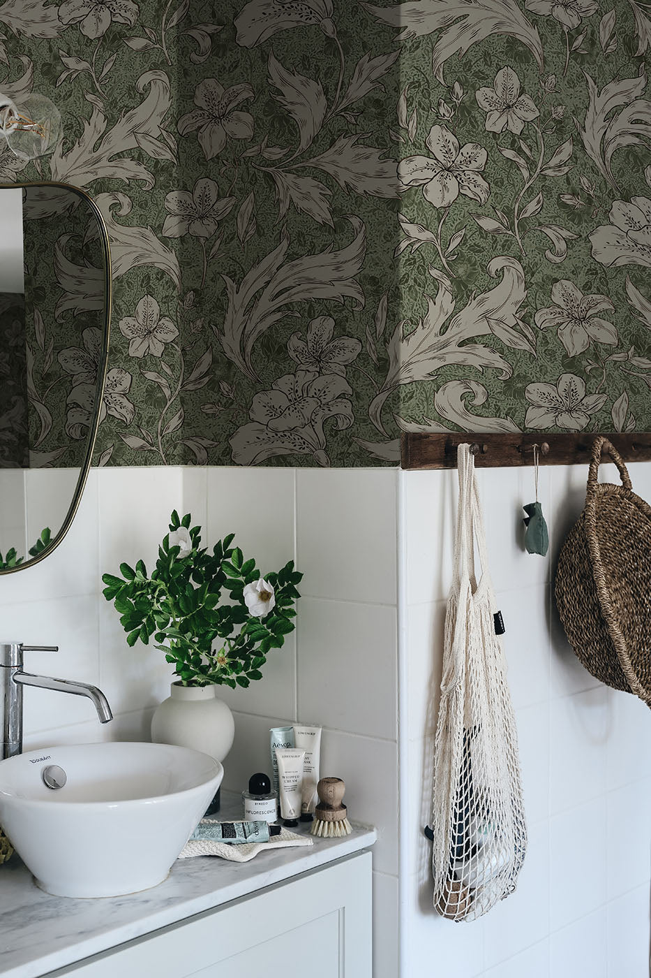 Mattias wallpaper by Sandberg in deep green, lily and acanthus design above white tiles in a styled bathroom