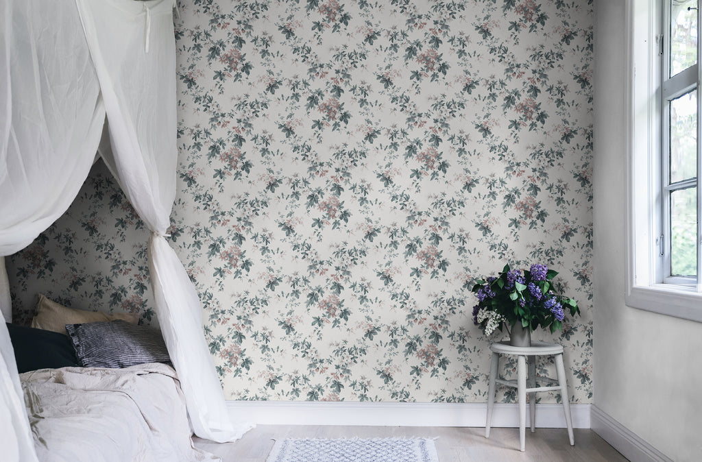 Sandra Floral wallpaper by Sandberg in cream, styled in a bedroom with the soft floral print behind a canopy bed and lilac flowers