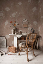 Poppy wallpaper by Sandberg in taupe, styled in a home office with a fluted white desk, rattan chair and orange ranunculus