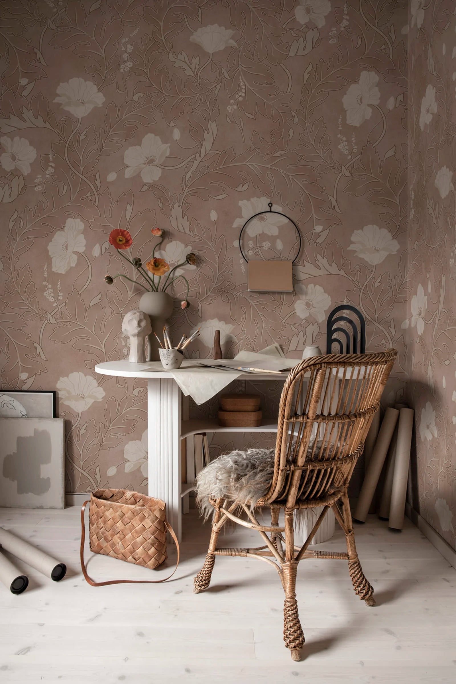 Poppy wallpaper by Sandberg in taupe, styled in a home office with a fluted white desk, rattan chair and orange ranunculus