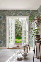 Poppy wallpaper by Sandberg in sage green with blue poppies, styled in a sunlit room with open French doors to a garden