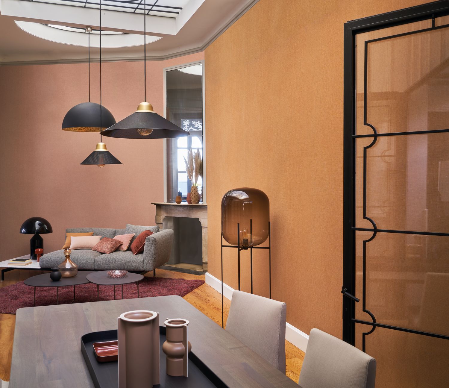Filin wallpaper by Casamance in saffron, a plain textured finish styled in a living room with black pendant lights and a marble fireplace