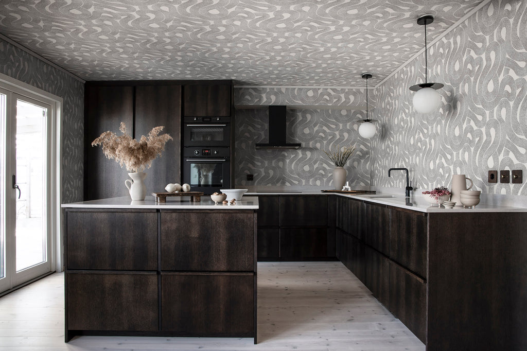 Zen wallpaper by Sandberg in charcoal looping print across the walls and ceiling of a dark timber kitchen