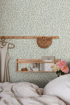 Karolina sage-green leaf wallpaper by Sandberg above a bed with oak shelf and peonies in a styled bedroom
