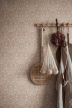 Emil wallpaper by Sandberg in dusty pink on a wall with peg rail holding a net bag and linen apron