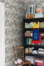 Ragnvi wallpaper by Sandberg in a craft corner, grey blossom tree pattern beside a black shelf and timber chair