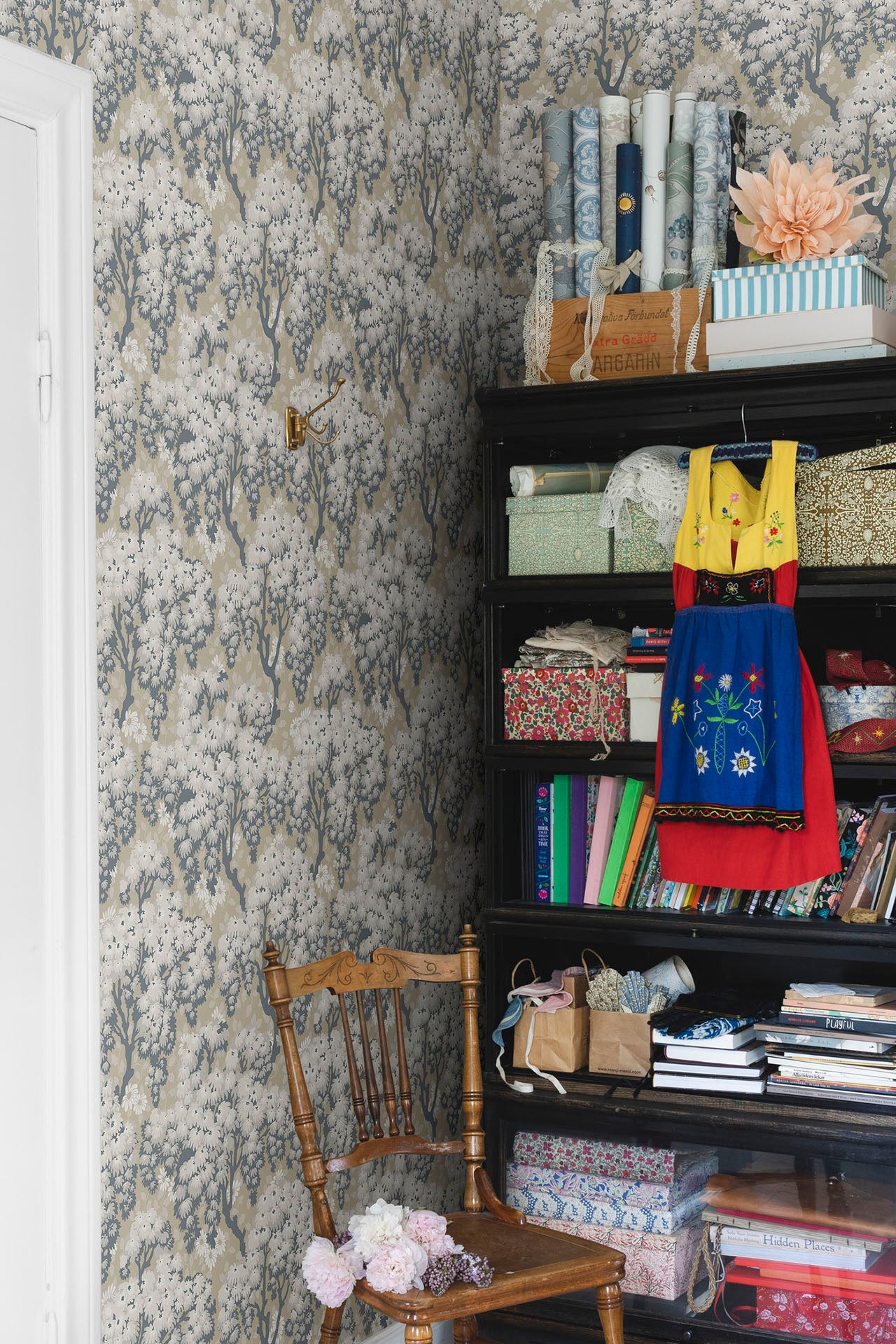 Ragnvi wallpaper by Sandberg in a craft corner, grey blossom tree pattern beside a black shelf and timber chair