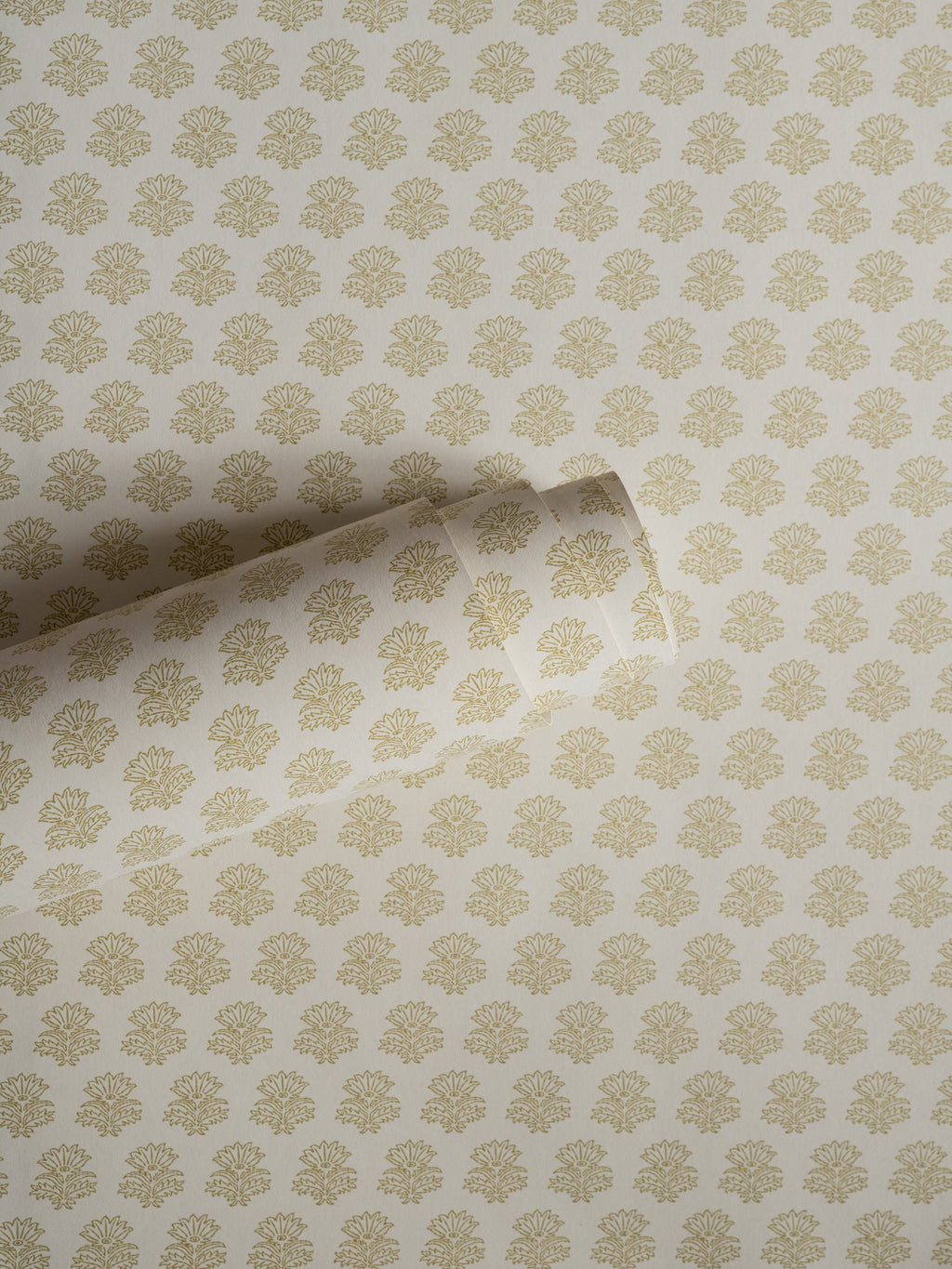 India wallpaper by Långelid/von Brömssen in Yellow – floral design, a part-rolled length showing the block-print flower