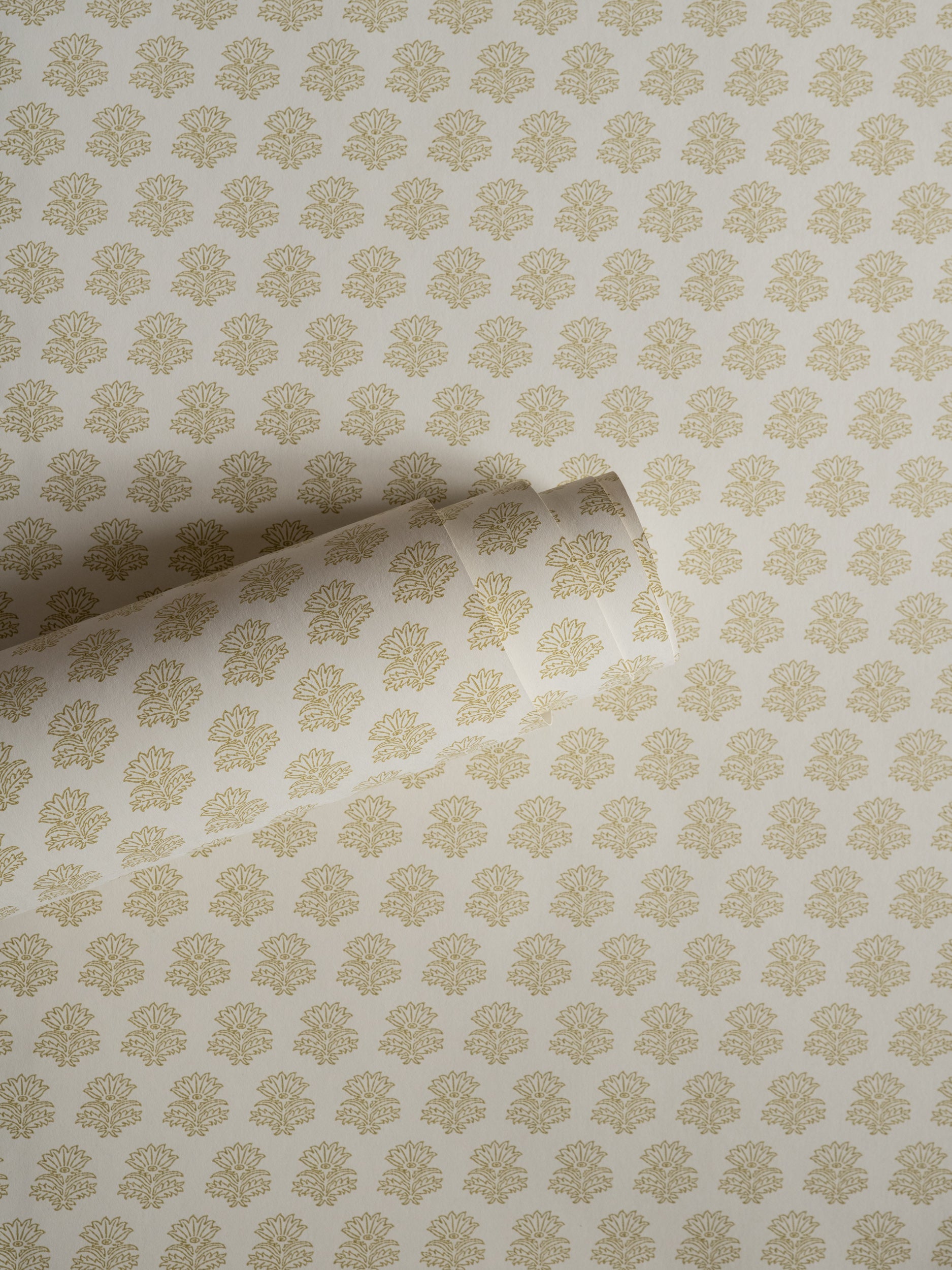 India wallpaper by Långelid/von Brömssen in Yellow – floral design, a part-rolled length showing the block-print flower