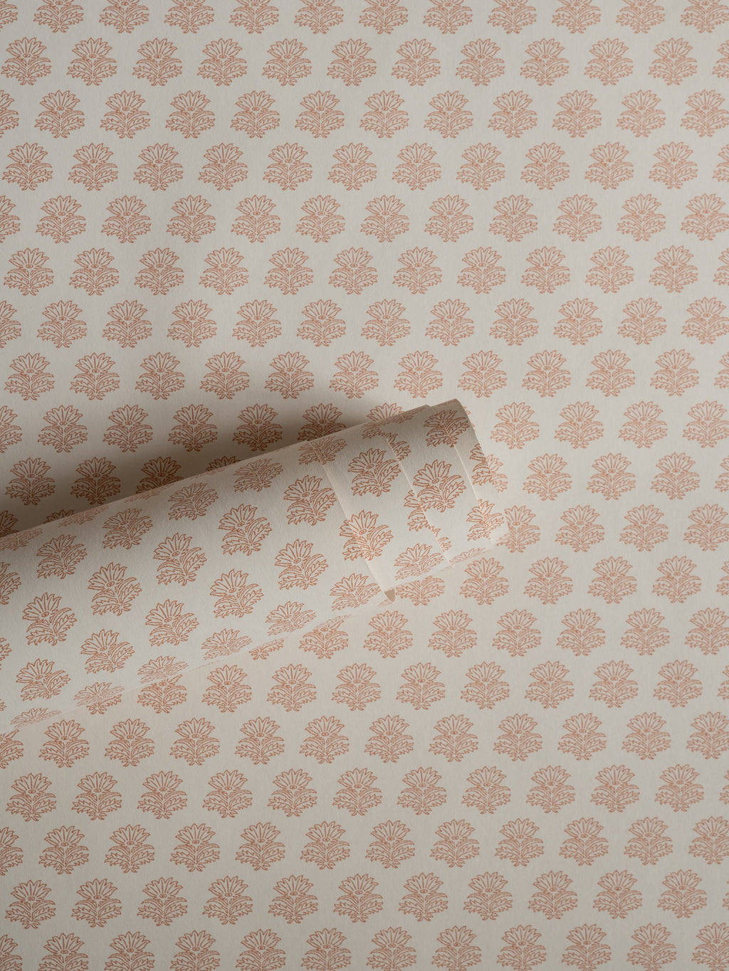India wallpaper by Långelid/von Brömssen in Peach – floral design, a part-rolled length showing the block-print flower