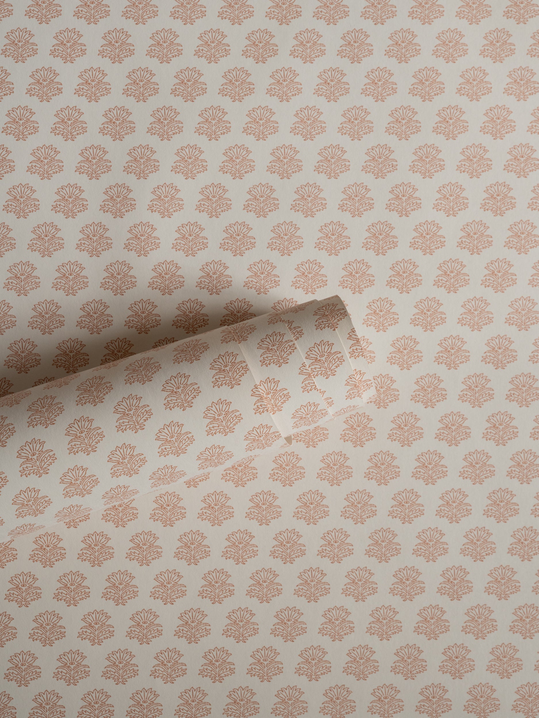 India wallpaper by Långelid/von Brömssen in Peach – floral design, a part-rolled length showing the block-print flower