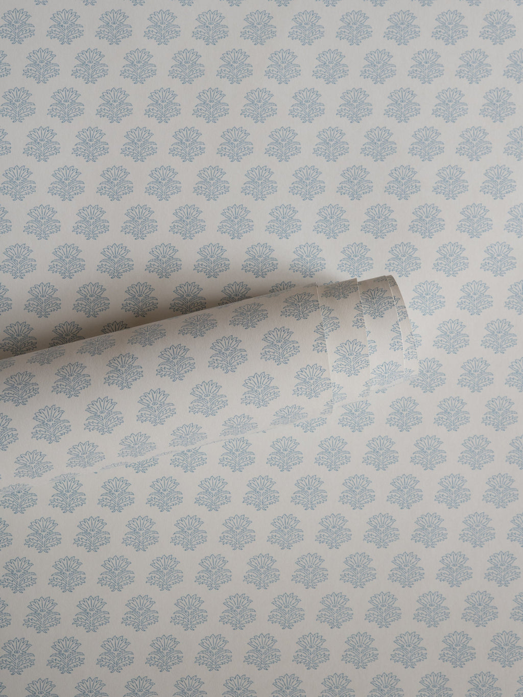 India wallpaper by Långelid/von Brömssen in Blue – floral design, a part-rolled length showing the block-print flower