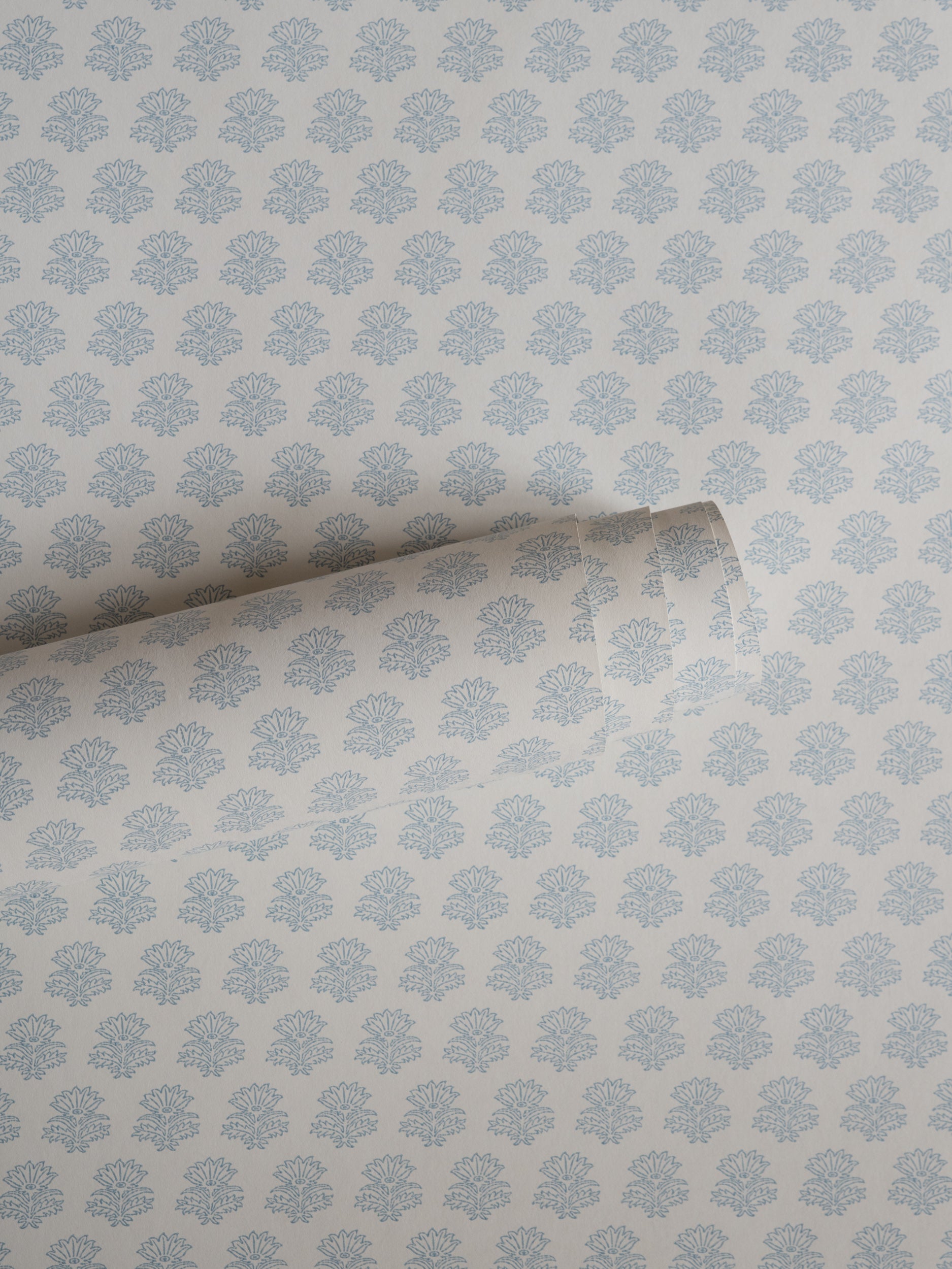 India wallpaper by Långelid/von Brömssen in Blue – floral design, a part-rolled length showing the block-print flower