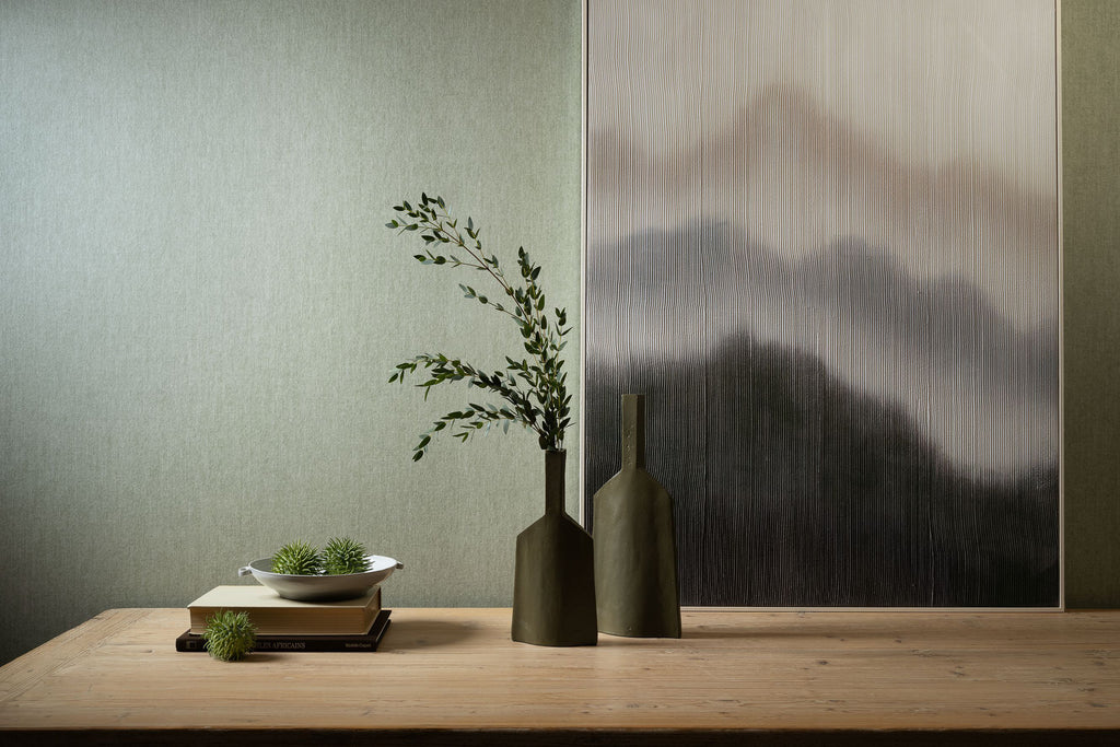 Flamant Terre de Lin wallpaper by Arte in Green – Vert d'Eau behind a timber shelf with a vase and a landscape artwork