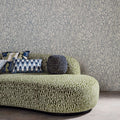 Edenfield wallpaper by Harlequin in a grey wood-grain moire design, styled behind a green sculptural sofa in a living room