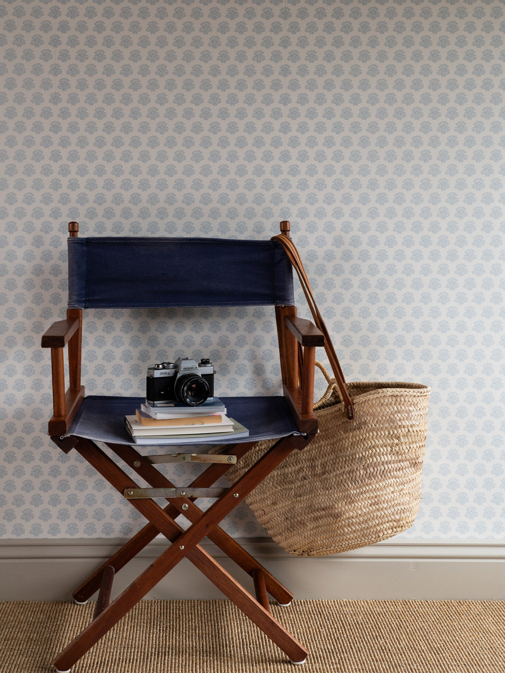 India wallpaper by Långelid/von Brömssen in Blue – floral design, behind a director's chair and a woven bag