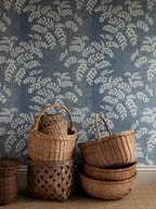 Acacia wallpaper by Långelid/von Brömssen in Blue – botanical design, with a stack of wicker baskets