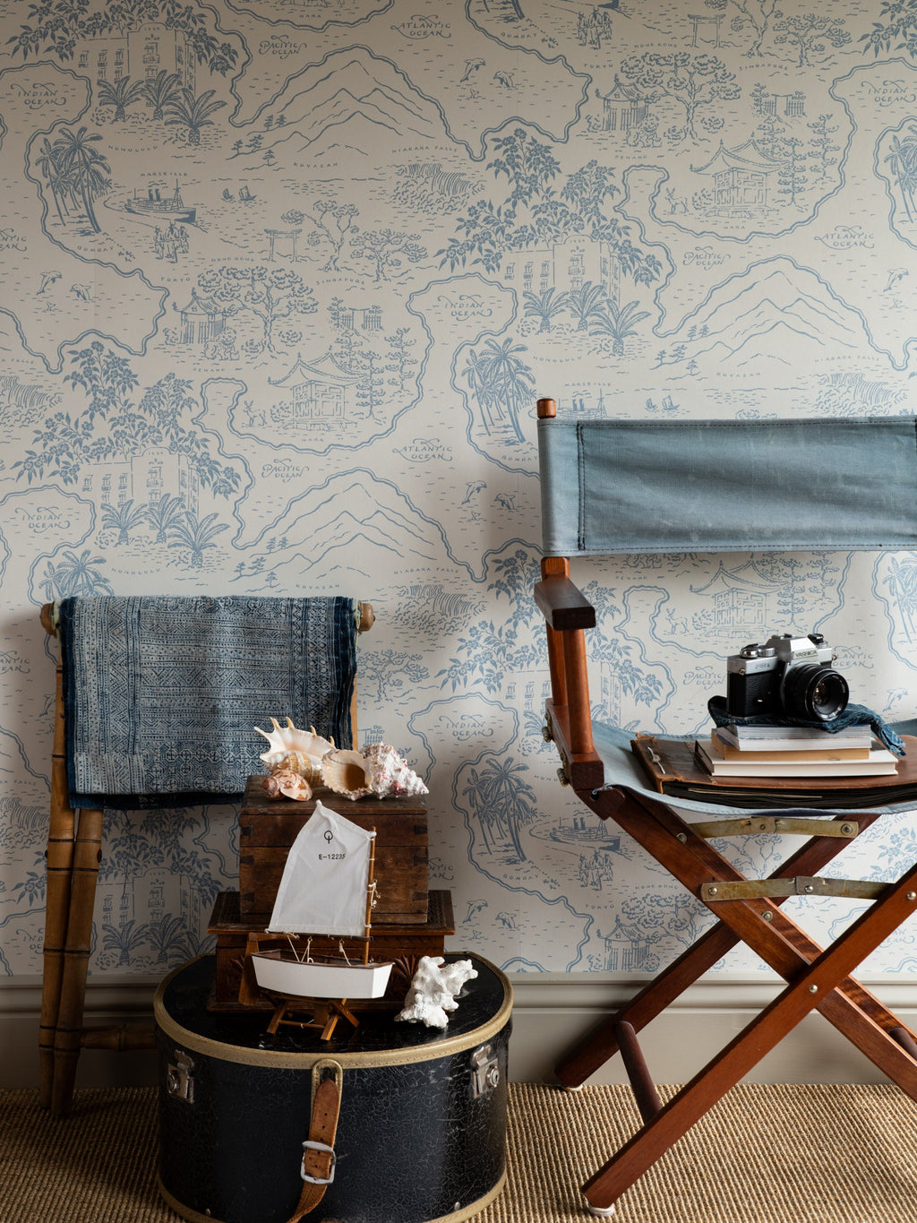 Voyage 1929 wallpaper by Långelid/von Brömssen in Blue – coastal design, behind a director's chair and a black travel trunk