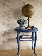 Voyage 1929 wallpaper by Långelid/von Brömssen in Orange – coastal design, behind a blue side table with a globe and hydrangeas