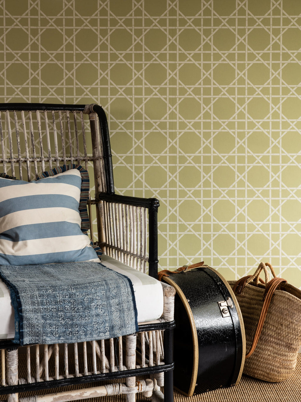 Trellis wallpaper by Långelid/von Brömssen in Green – geometric design, behind a rattan armchair with striped cushions