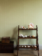 Zigzag wallpaper by Långelid/von Brömssen in Green – Dusty Lemon – geometric design, behind a wooden shelf of shells