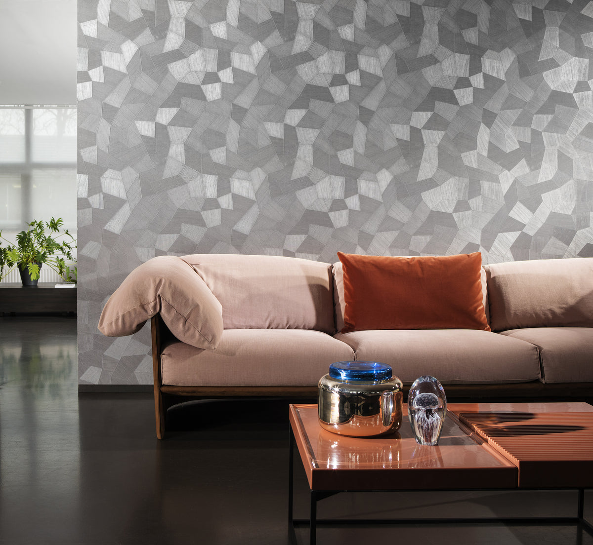 Facet wallpaper by Arte in Grey – Pigeon behind a blush sofa and a copper coffee table
