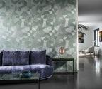 Facet wallpaper by Arte in Green – Eucalyptus behind a purple velvet sofa in an open living space