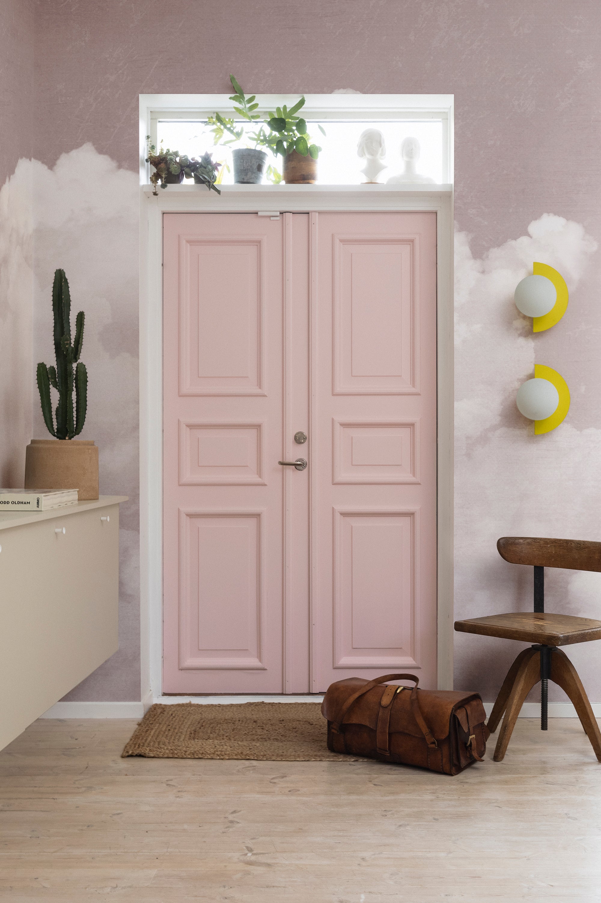 Fluffy Clouds wall mural by Rebel Walls in blush pink, framing a pink panelled door in a bright hallway