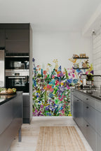 May Meadow mural by Rebel Walls, colourful watercolour wildflowers on a kitchen feature wall above dark grey cabinetry