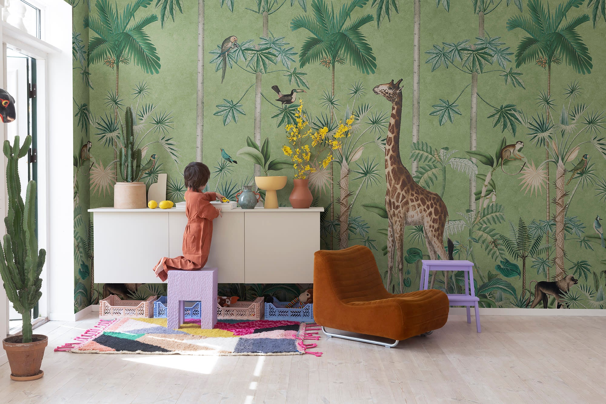Giraffe's Stroll wallpaper by Rebel Walls in Green, styled on an interior wall