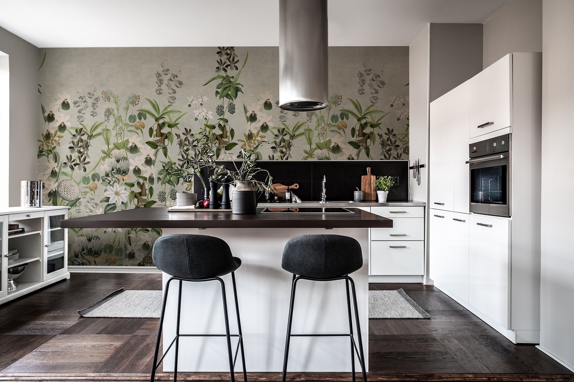 Alice's Garden Mural by Rebel Walls in sage green styled behind a modern white kitchen island and stools