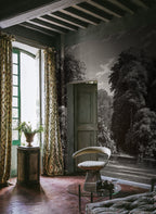 Spring Season wall mural by Rebel Walls, etched charcoal-grey woodland scene, styled in a rustic room with a velvet chair and tall floral drapes