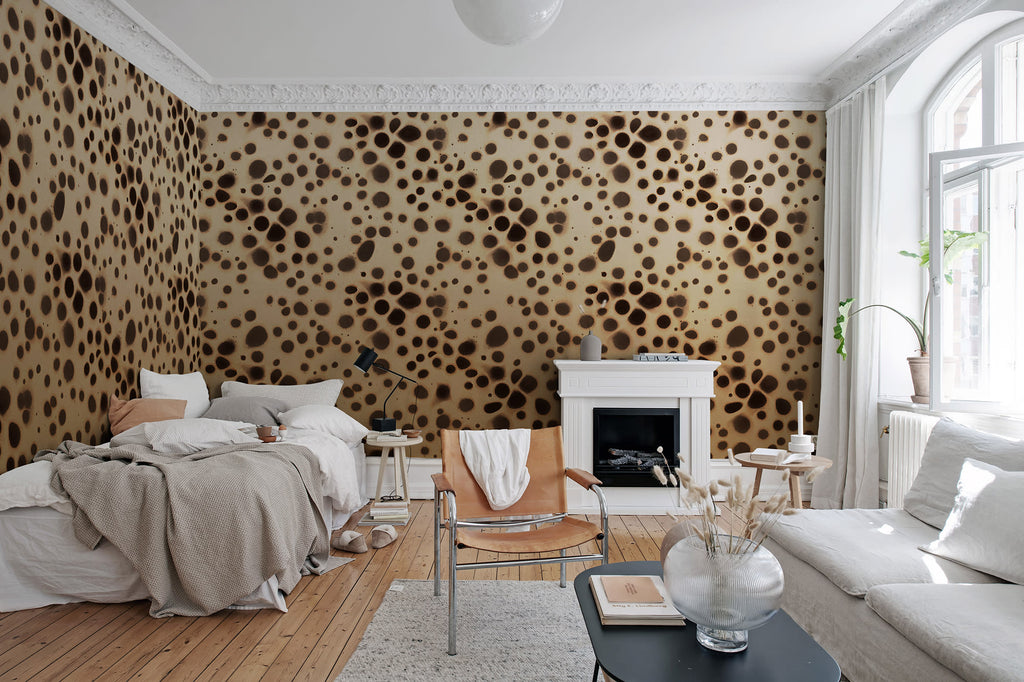Spotted Puffer wall mural by Rebel Walls, dark brown spots on cream, in a bedroom with white fireplace and leather chair