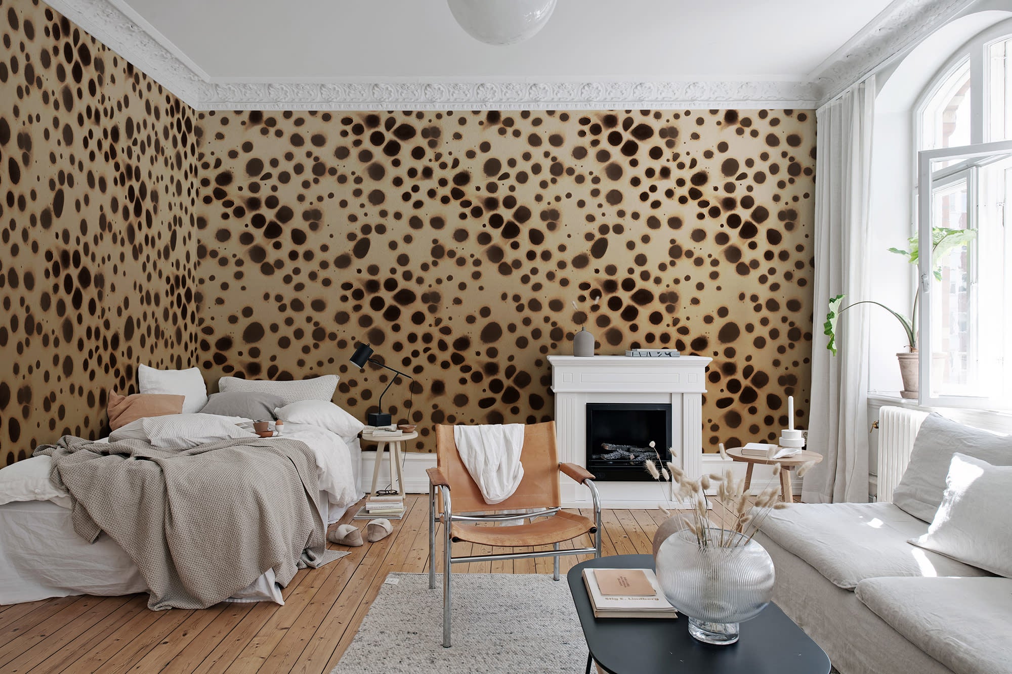 Spotted Puffer wall mural by Rebel Walls, dark brown spots on cream, in a bedroom with white fireplace and leather chair