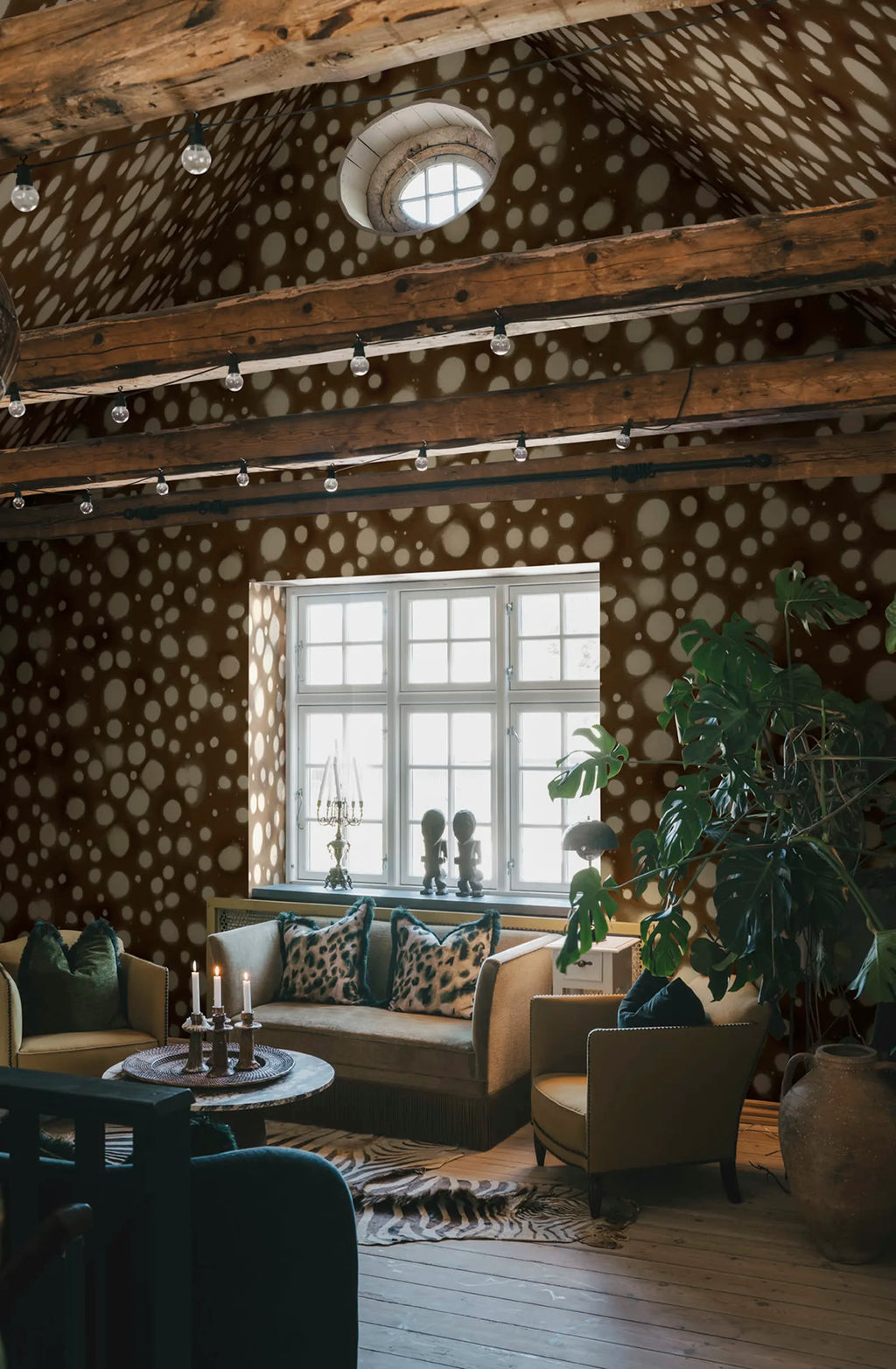 Spotted Puffer wall mural by Rebel Walls in cream-on-brown spots, in an attic lounge with timber beams and skylight