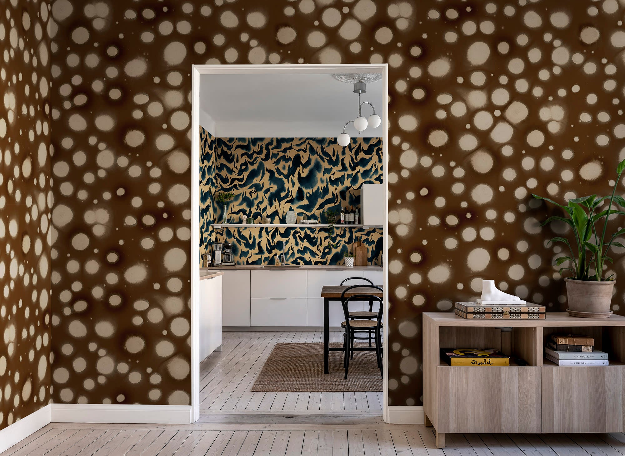 Spotted Puffer wall mural by Rebel Walls, cream dots on dark brown, framing a doorway into a navy-walled dining room