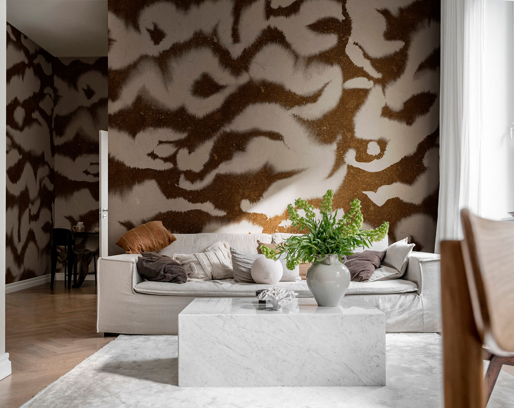 Guppy wall mural by Rebel Walls, brown and cream watercolour ikat swirls, styled in a living room behind a white sofa