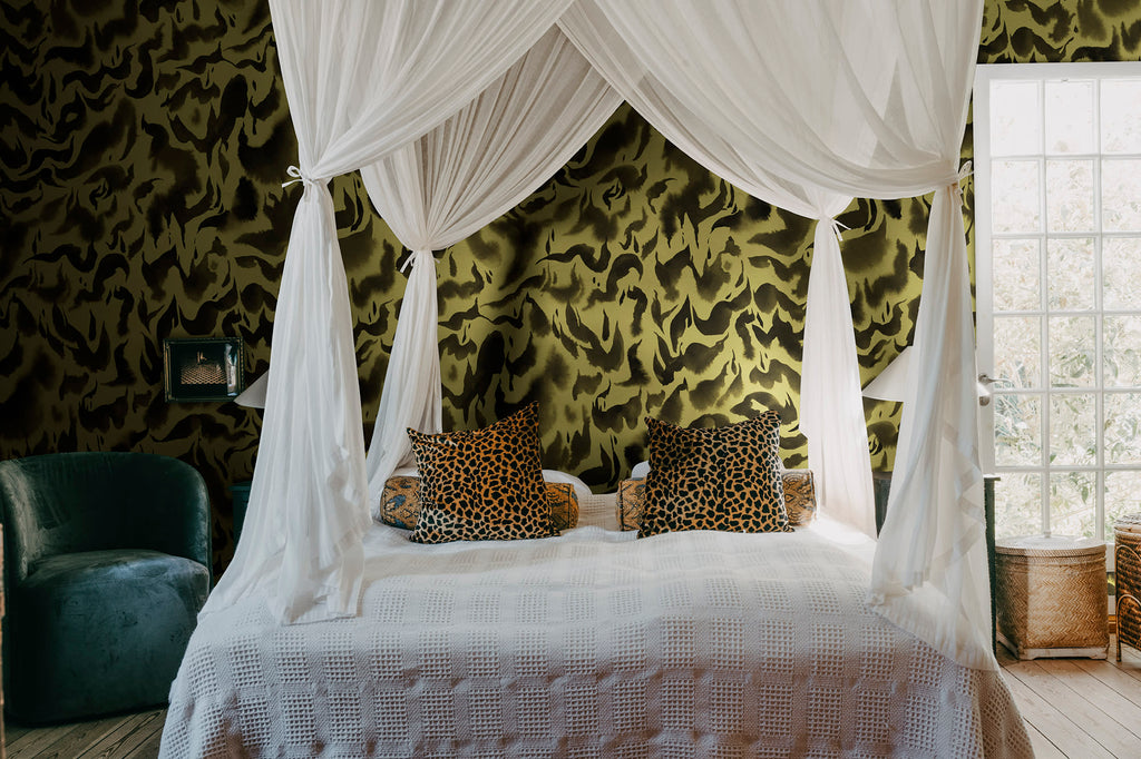 Discus Fish wall mural by Rebel Walls in olive yellow and black swirls, behind a canopy bed with leopard cushions