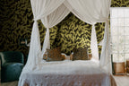 Discus Fish wall mural by Rebel Walls in olive yellow and black swirls, behind a canopy bed with leopard cushions