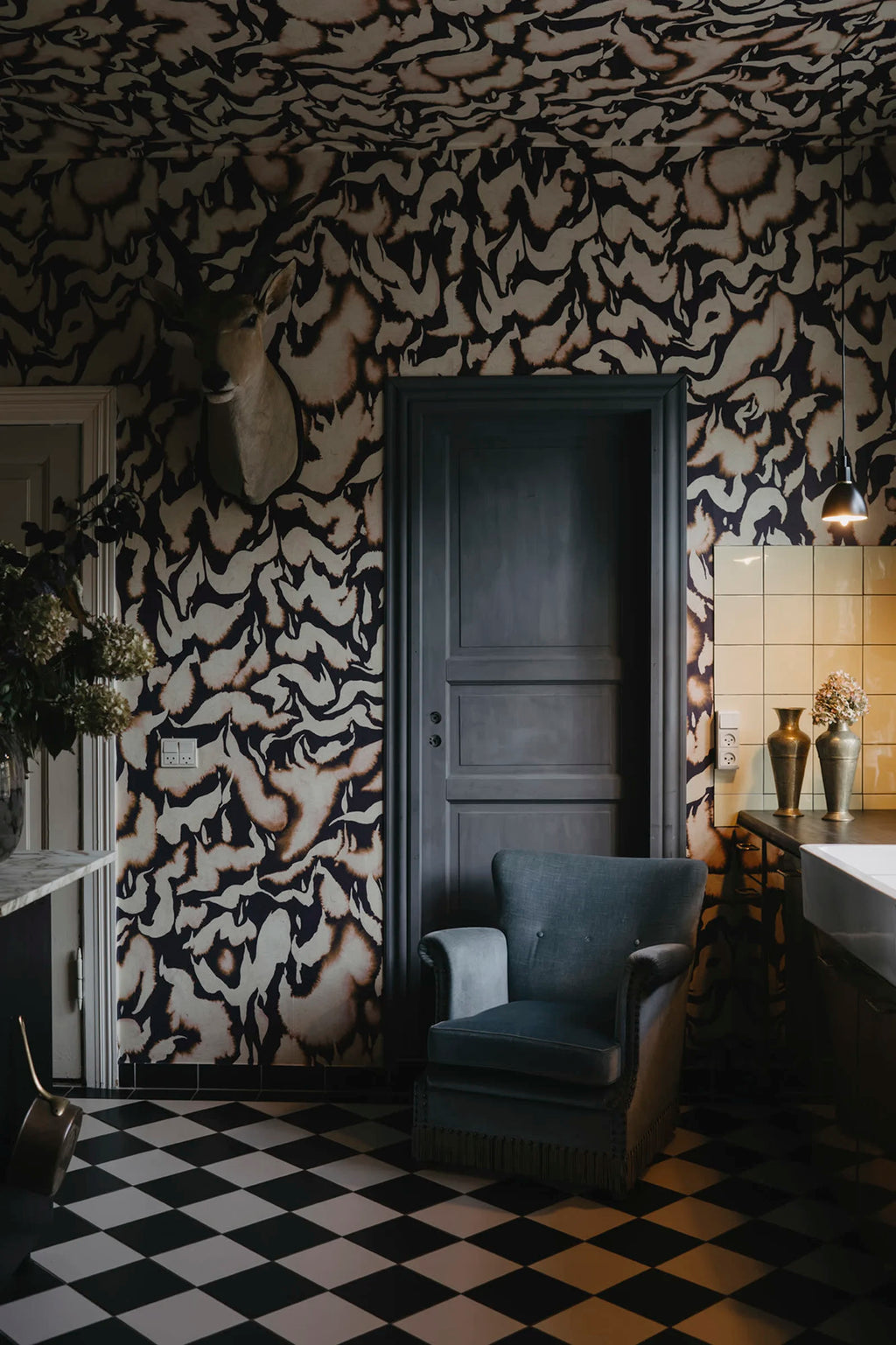 Discus Fish wall mural by Rebel Walls in plum and cream swirls, behind a grey door and velvet armchair on checkerboard floor