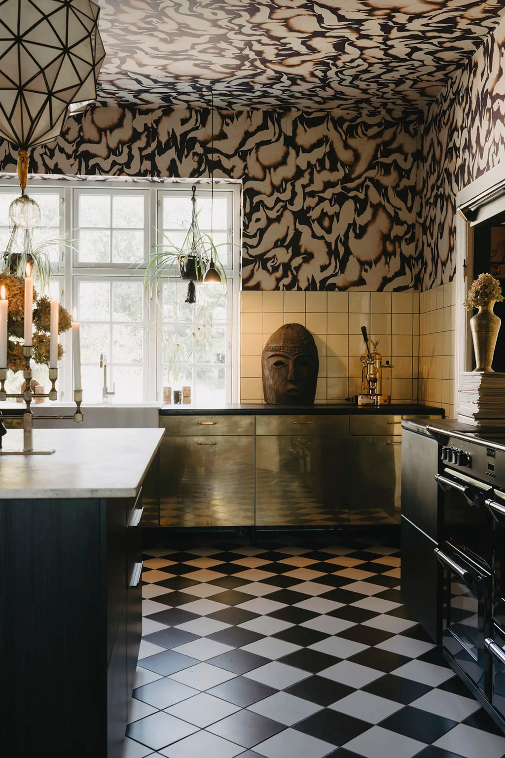 Discus Fish wall mural by Rebel Walls in plum and cream swirls on walls and ceiling of a kitchen with brass cabinets