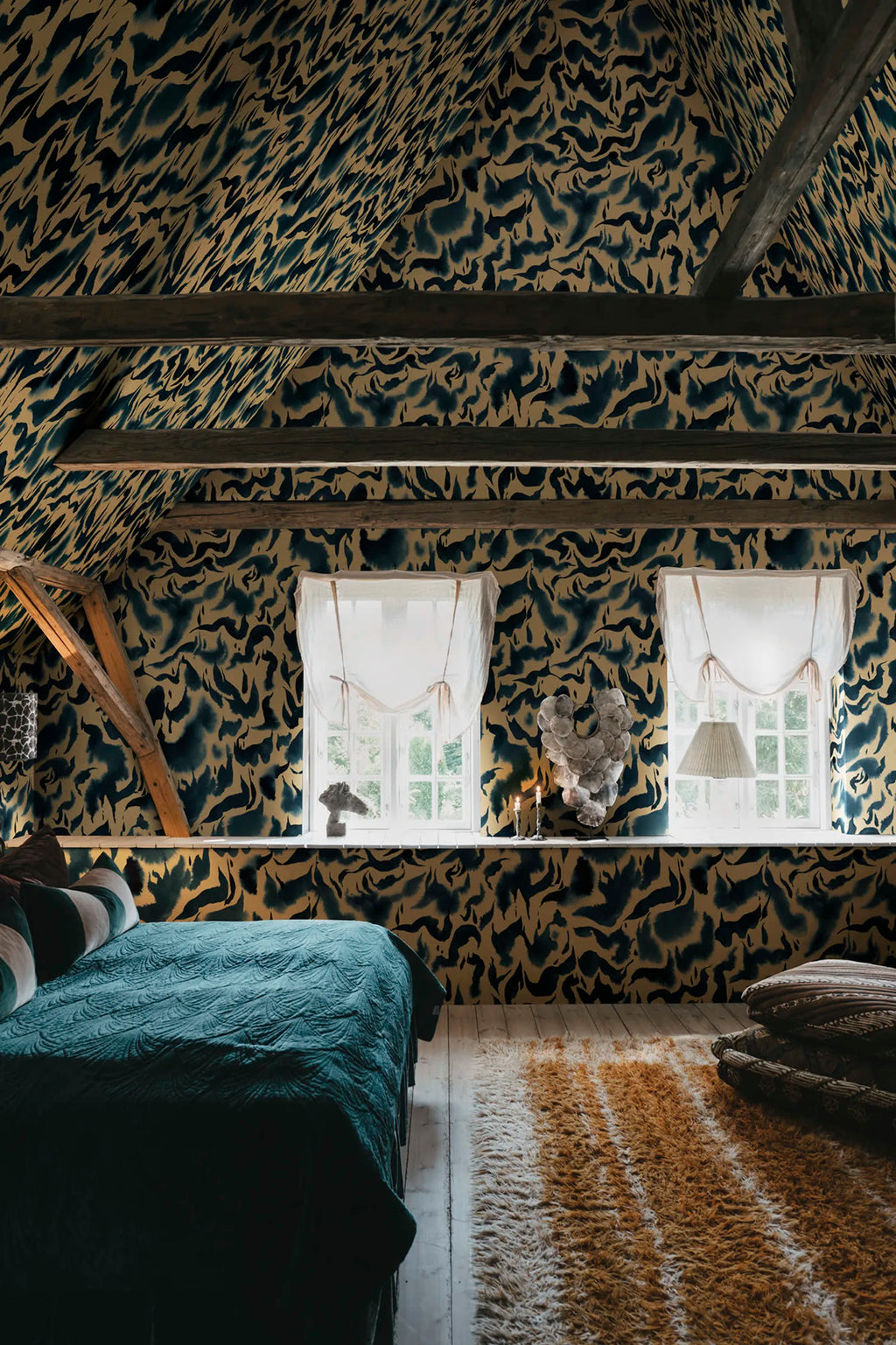 Discus Fish wall mural by Rebel Walls in navy and gold swirls covering an attic bedroom with timber beams