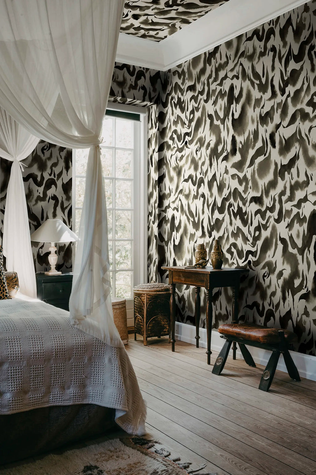 Discus Fish wall mural by Rebel Walls in black and cream swirls, behind a canopy bed with antique writing desk