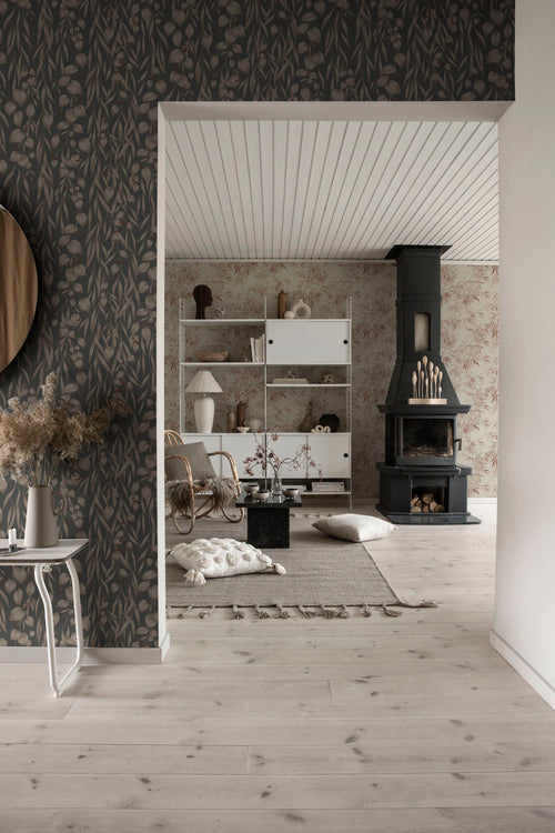 Sara wallpaper by Sandberg in charcoal on a feature wall, trailing eucalyptus pattern beside a doorway into a bright living