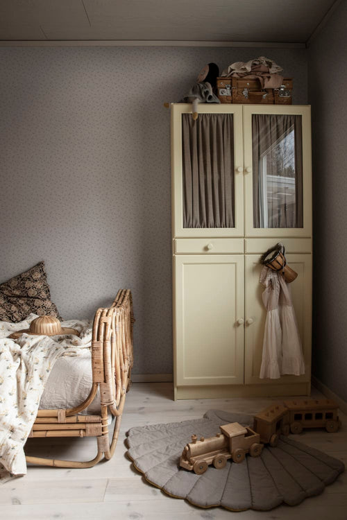 Stella wallpaper by Sandberg covering a cosy kids' bedroom wall beside a cream wardrobe and rattan bed