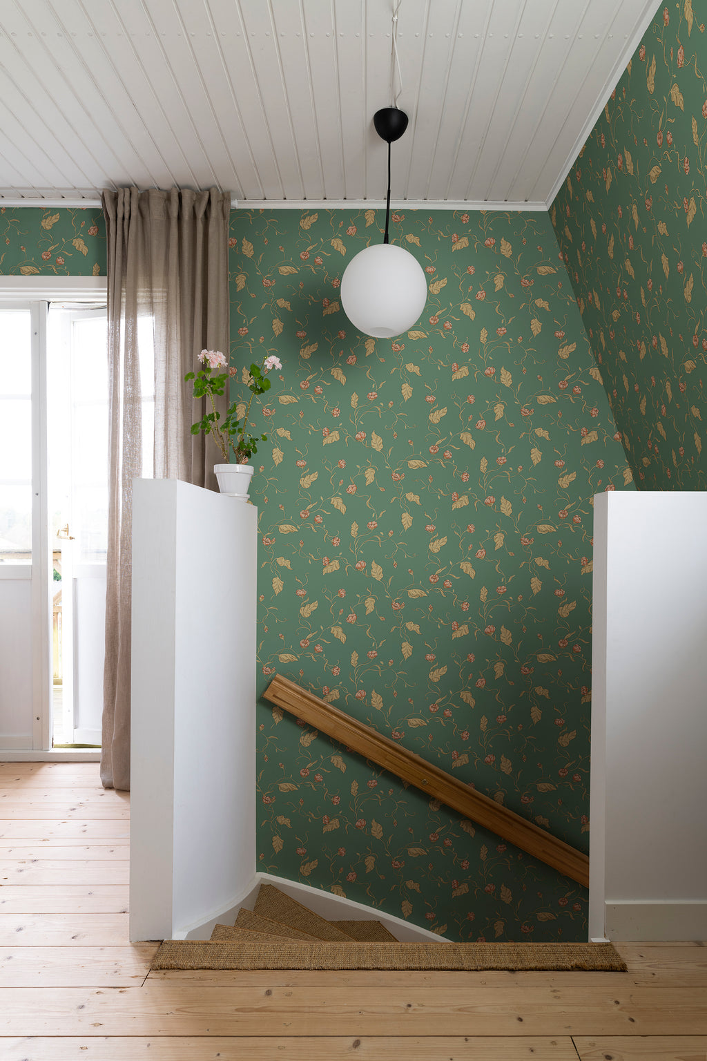 Elmire wallpaper by Sandberg in green on a stairwell landing with a globe pendant light and pine floor